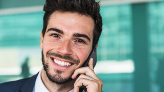 poslovnež ima telefonski klic in se smehlja