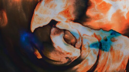 Abstraktni valovi različnih odtenkov oranžno-rdeče.