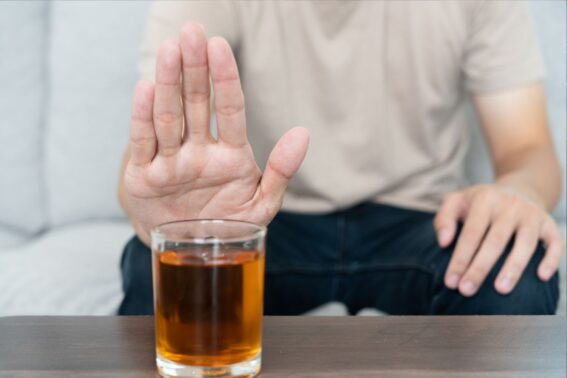Moški s stegnjeno dlanjo nakazuje, da ne bo pil alkoholne pijače, ki je pred njim na mizi.