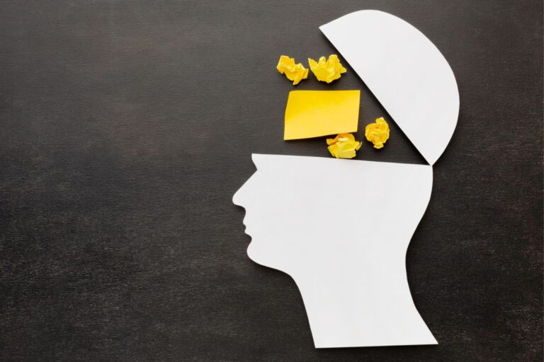 Stranski profil človeške glave, ki ima lobanjo na pol odprto, znotraj odprtine pa so štirje zmečkani rumeni listki in en, ki ni zmečkan.